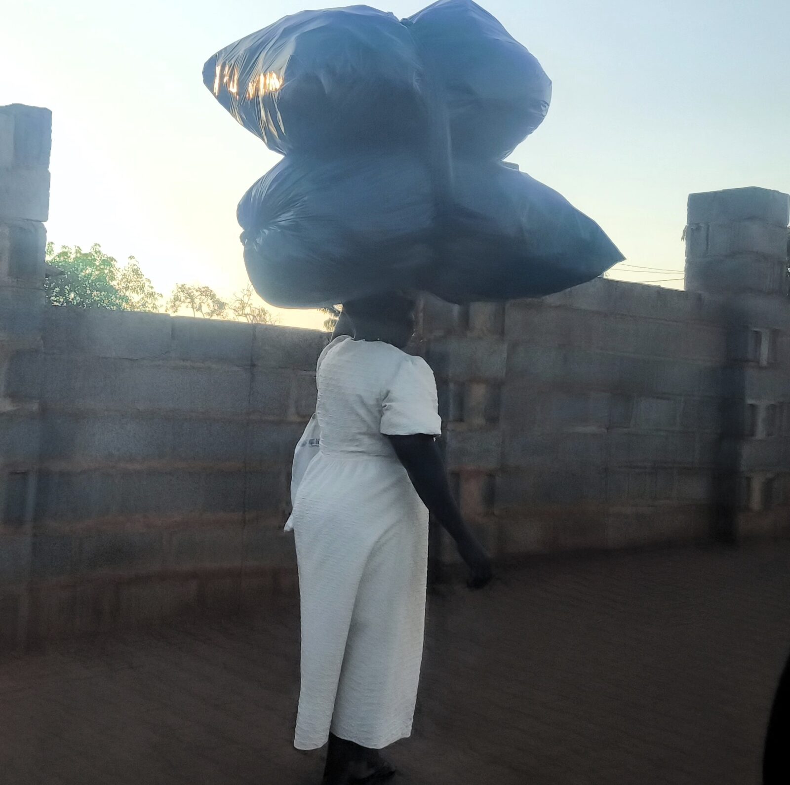 Frau transportiert Sachen auf dem Kopf